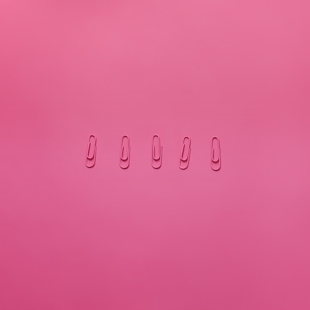 Roze paperclips op de roze achtergrond. Horizontaal