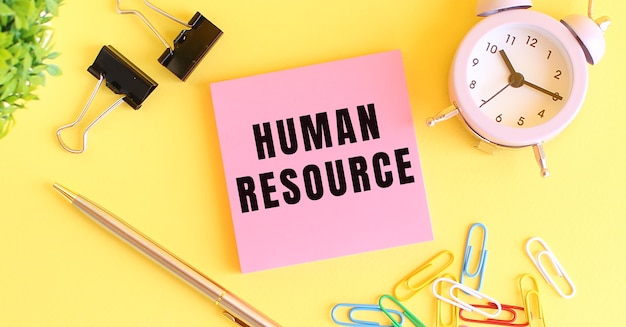 Roze papier met de tekst human resource klokpen op een gele achtergrond