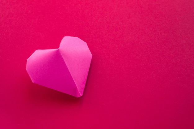 Roze papieren hart origami geïsoleerd op een rode achtergrond