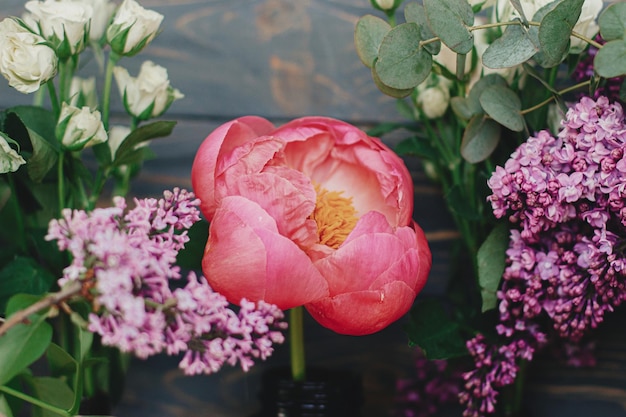 Roze peony lila eucalyptus rozen bloemen op donker rustiek hout Lente stijlvol boeket stilleven