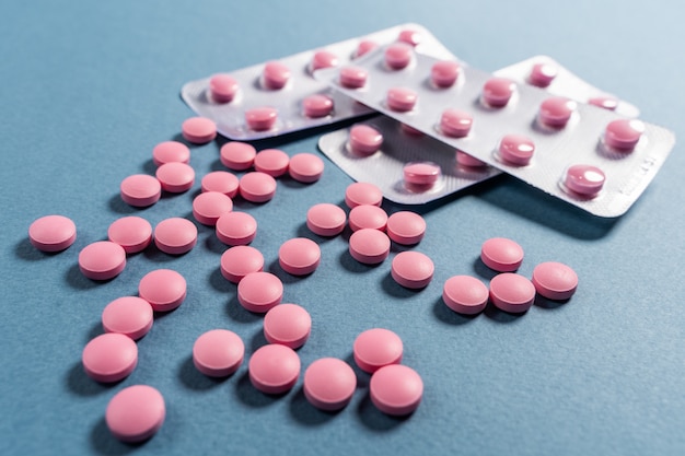 Roze pillen in een blaar op een blauwe achtergrond