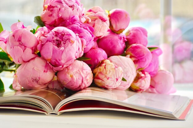 Roze pioenrozen en boek Je favoriete boek lezen Bloemen achtergrond Bloemen liggen op open boek