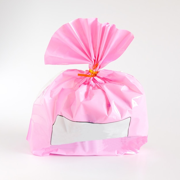 Foto roze plastic cadeauzakje met lint op wit.