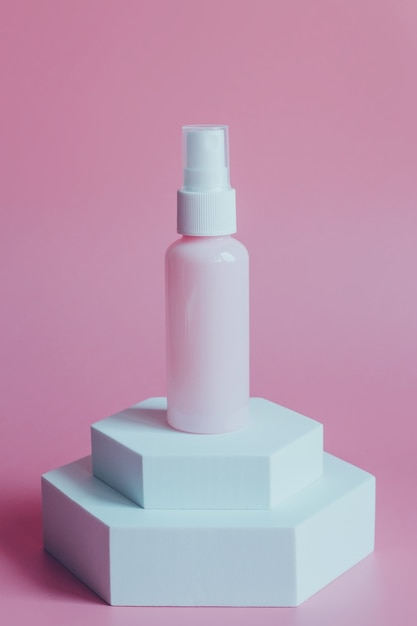 Roze plastic flessencontainer voor cosmetica, op een wit platform