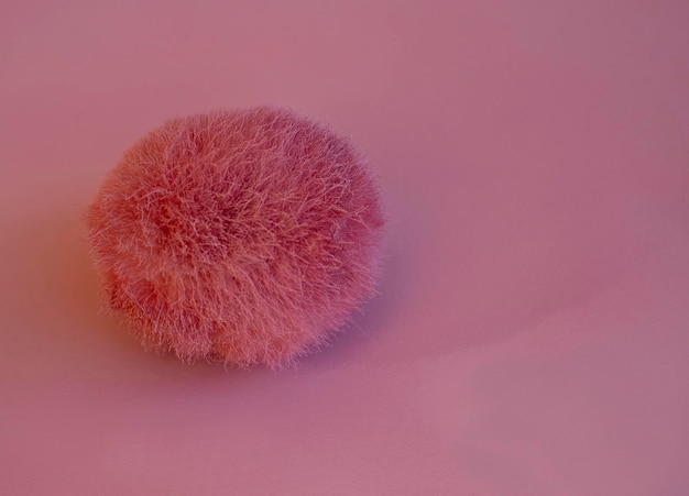 Foto roze pluizige bal bont pompon geïsoleerd op roze fluffy roze namaakbont bal pompon een speeltje voor een kat