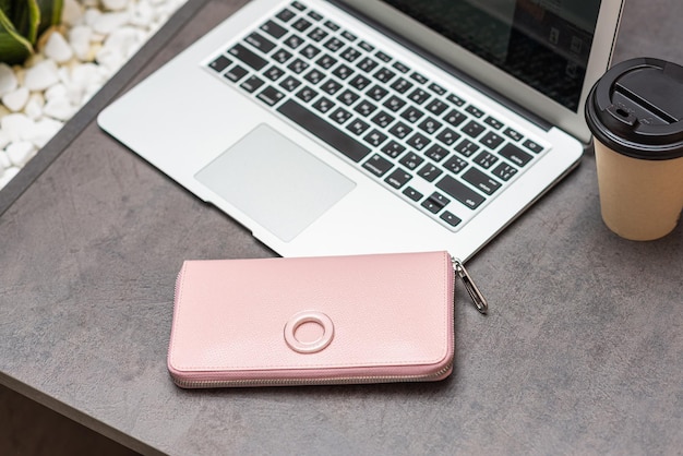 Roze portemonnee ligt op tafel naast de laptop