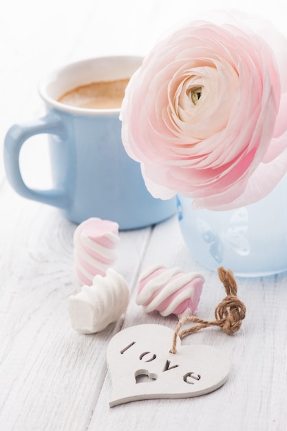 Roze ranunculus en mok koffie