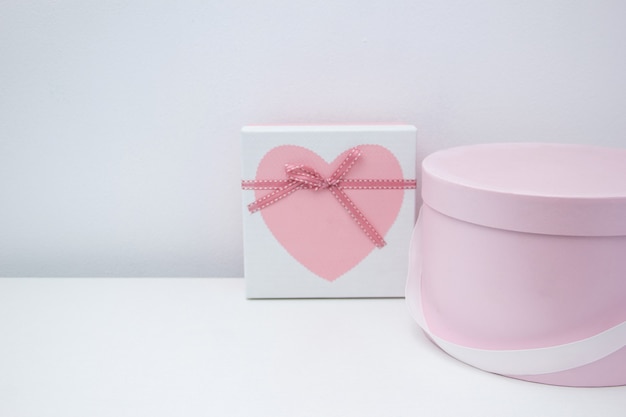 Roze romantische geschenkdoos met witte satijnen strik op een lichtblauwe houten stoel