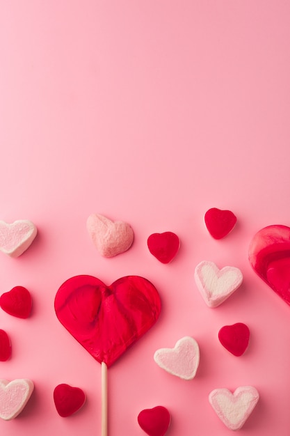 Roze romantische vakantie achtergrond met hartvormige zoete snoepjes. Decoratieve kaart voor Valentijnsdag met ruimte voor tekst. Liefdesthema.