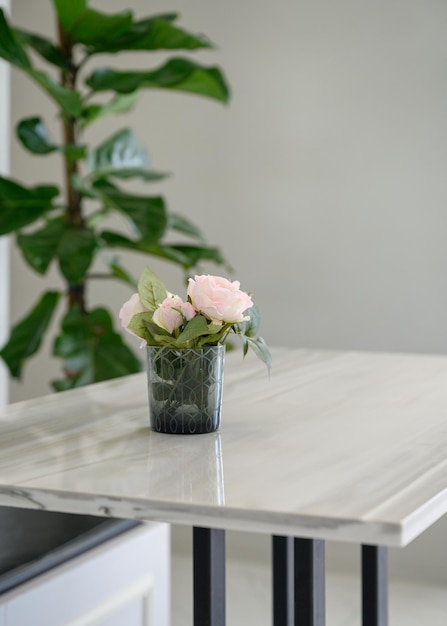 Roze roos bloeiend in glas op houten tafel