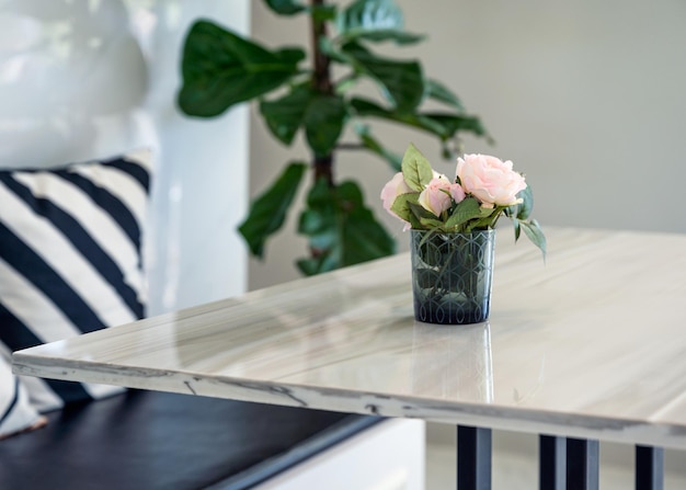 Roze roos bloeiend in glas op houten tafel