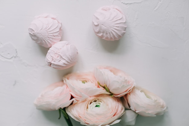 Roze roze bloemen en marshmallows op een witte ondergrond