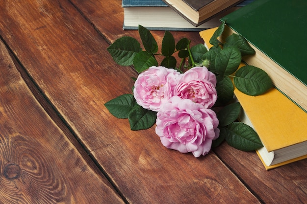 Roze rozen en boek met een gele kaft op een houten oppervlak