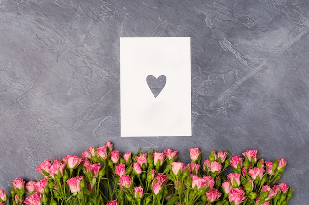 Roze rozen en cadeau witte kaart met hart op grijze achtergrond Vrouw Valentijnsdag moederdag concept