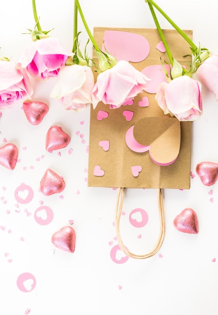 Roze rozen en handgemaakte cadeautas op een witte achtergrond.