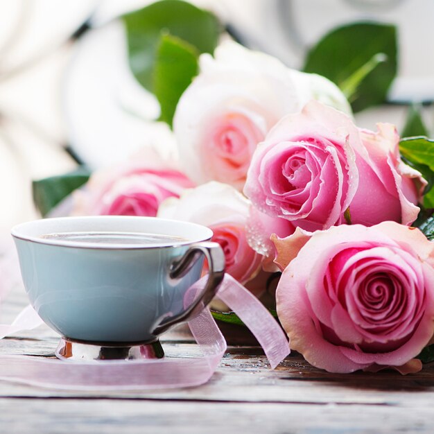 Roze rozen en koffie op de houten tafel