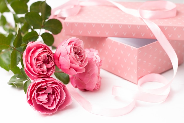 Roze rozen in de buurt van een roze geschenkdoos
