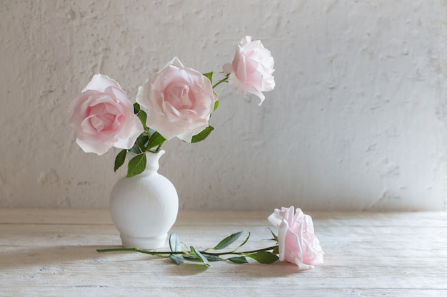 Roze rozen in vaas op witte muur