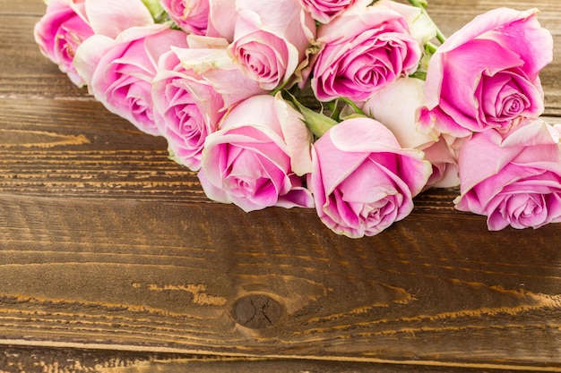 Roze rozen op houten tafel.