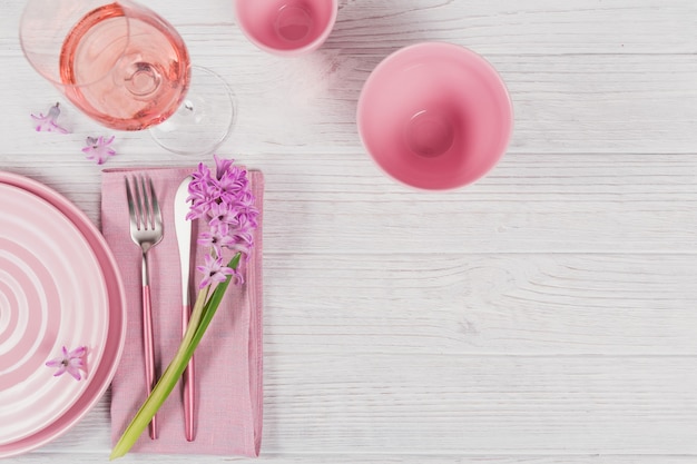 Roze rustieke couvert met paarse hyacint bloem en linnen servet en glas rose wijn op witte houten oppervlak