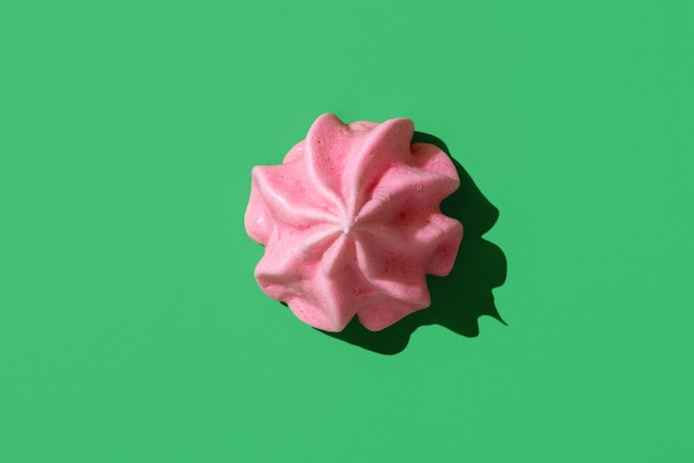 Roze schuimgebakjekoekje minimalistisch op een groene hoogste mening als achtergrond