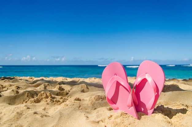 Roze slippers op het zandstrand