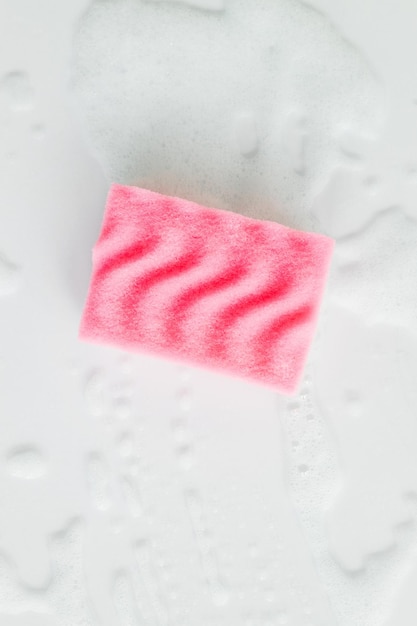 Roze spons met wasmiddel schuim op witte achtergrond close-up Schoonmaak concept