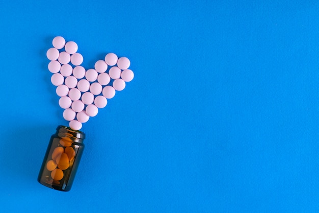 Roze tabletten worden gegoten in een glazen bruine bubbel in de vorm van een hart