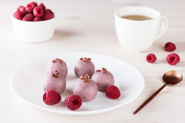 Roze truffels met frambozen op een wit bord suiker gluten en lactose vrij vegan