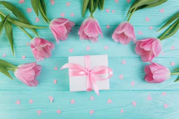 Roze tulpen, cadeau en papier harten op blauwe houten achtergrond