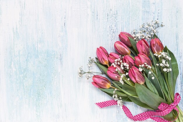 Roze tulpen en gipskruid bloemen versierd met lint op blauwe achtergrond bovenaanzicht kopie ruimte