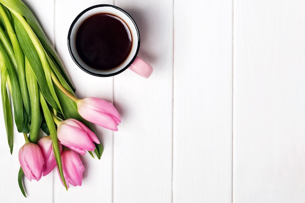 Roze tulpen en koffie in een mok op de witte tafel, bovenaanzicht