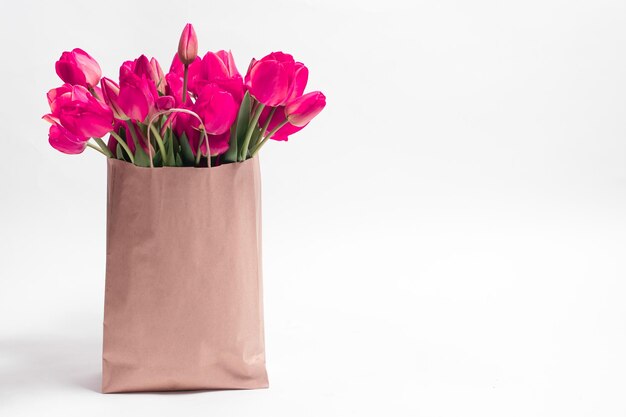 Roze tulpen in een ambachtelijke tas op een witte achtergrond met een plek voor tekst Gefeliciteerd met de vakantie verjaardag Valentijnsdag verjaardag Moederdag Dag van de leraar