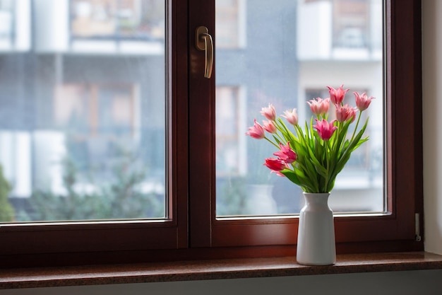 roze tulpen in een vaas op de vensterbank