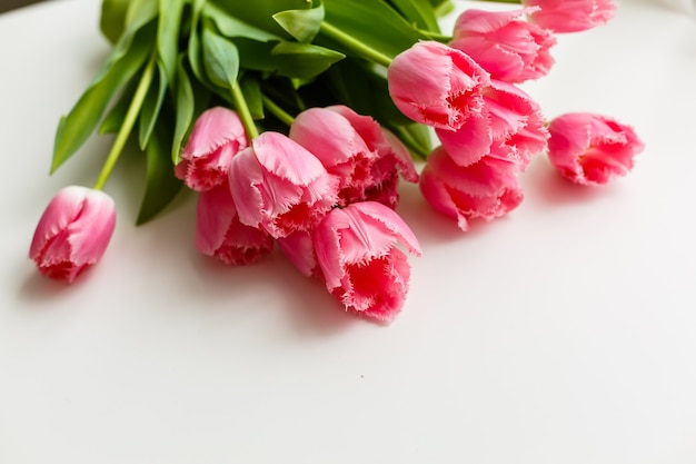 roze tulpen liggen op een witte tafel