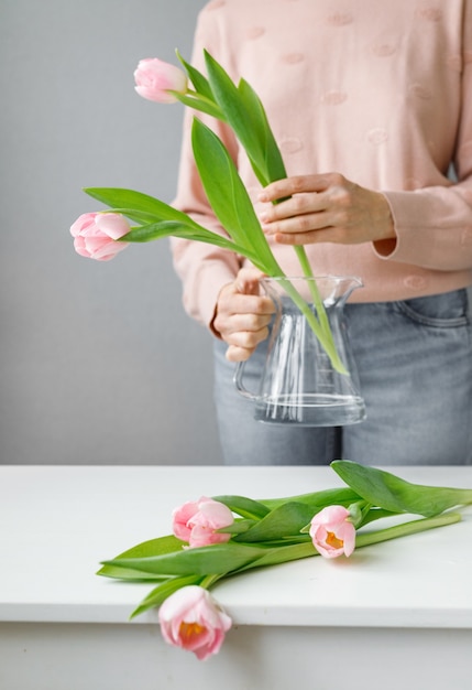 Roze tulpen met groene bladeren in een glazen vaas