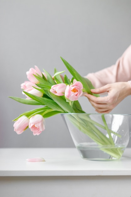 Roze tulpen met groene bladeren in een glazen vaas