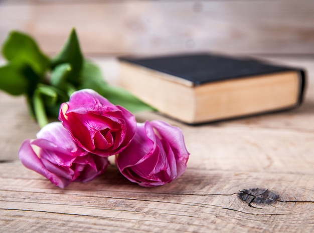 Roze tulpen met oud boek op houten tafel