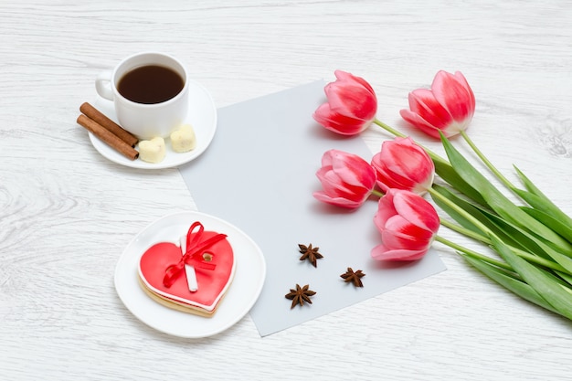 Roze tulpen, mok koffie en rode peperkoek