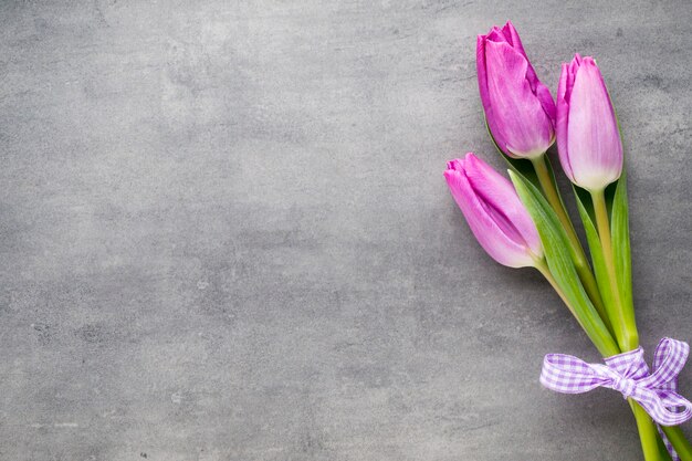 Roze tulpenbloemen met violet lint op het grijze oppervlak