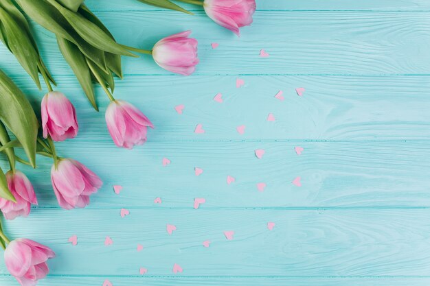 Roze tulpenboeket en document harten op blauwe houten achtergrond