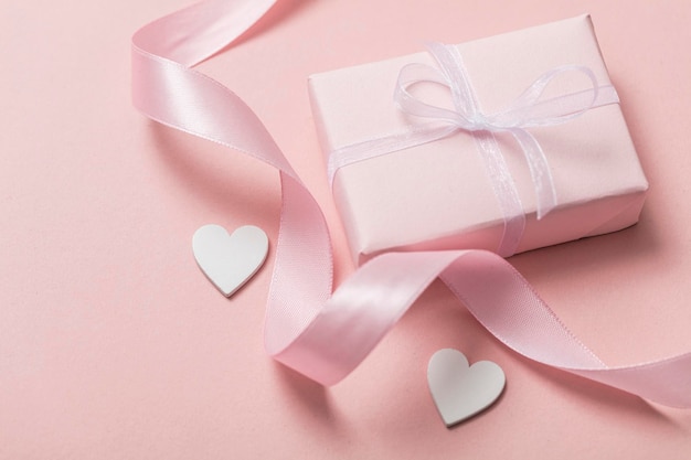 Roze valentijnscadeau met witte hartjes op een pastelroze achtergrond