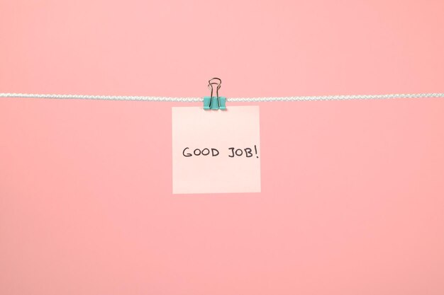 Roze vel papier aan het touwtje met tekst Good Job op kleurrijke achtergrond