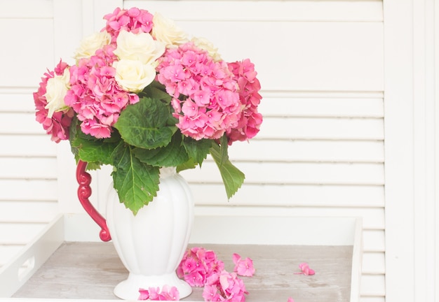 Roze verse hortensia bloemen met witte rozen in vaas op tafel