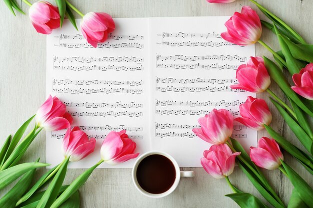 Roze verse tulpen over bladmuziek op de witte tafel, bovenaanzicht