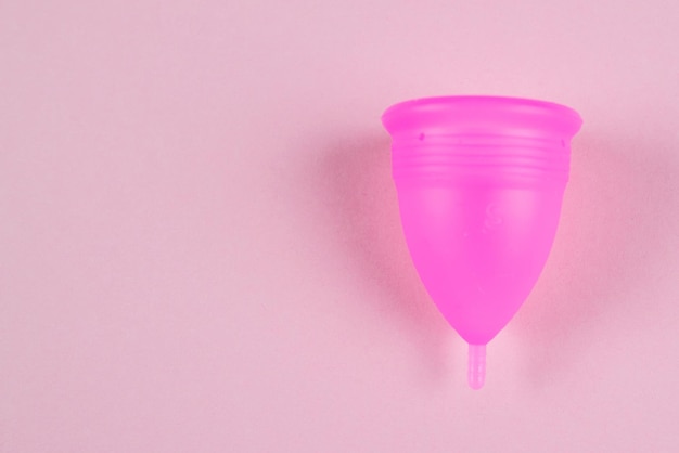 Roze vrouwelijke menstruatiecup op een roze achtergrond Vrouwelijke hygiëne Menstruatieplaats voor tekstkopieerruimte