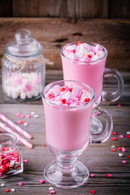 Roze warme chocolademelk met marshmallow en suikerharten in een glazen mok voor Valentijnsdag