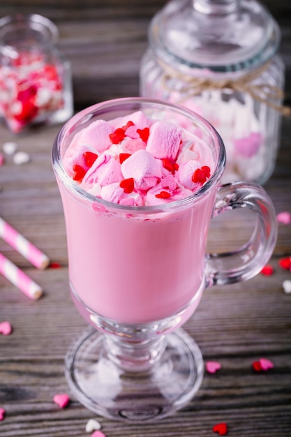 Roze warme chocolademelk met marshmallow en suikerharten in een glazen mok voor Valentijnsdag