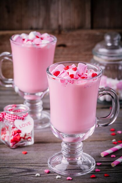 Roze warme melk met marshmallow en suikerharten in een glazen mok voor Valentijnsdag