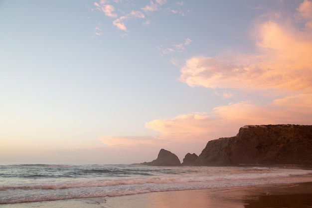 Roze wolk en zonsondergang op het strand van Odeceixe, Algarve, Portugal